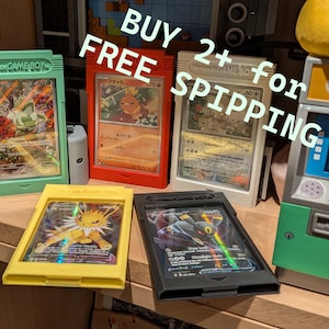 Puede incluir: Cartas coleccionables de Pokémon exhibidas en fundas protectoras con diseño de cartuchos de Game Boy. Las fundas son de colores verde, rojo, blanco, amarillo y negro. Se observa el texto "BUY 2+ for FREE SHIPPING".