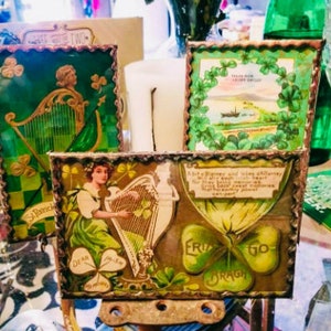 May include: Four vintage picture frames with green, gold, and white accents. The frames feature images of a harp, shamrocks, and a quote about Irish blessings. The frames are displayed on a table with a green tablecloth.