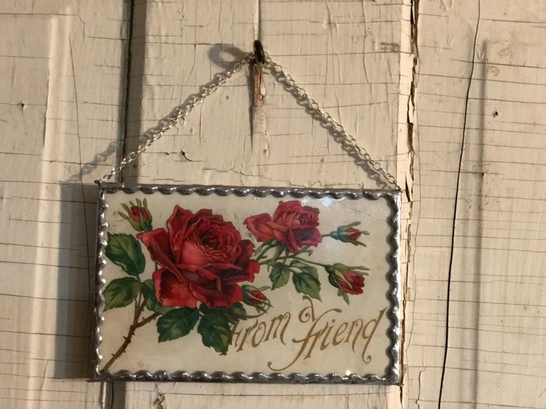 May include: A framed glass piece with a silver chain for hanging. The glass features a vintage image of red roses with green leaves and the text "from friend".
