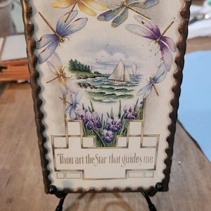 May include: Rectangular decorative panel with a coastal scene, irises, and dragonflies. The panel features a sailboat on the water, a lighthouse, and the text "Thou art the Star that guides me." The frame is bronze-colored.