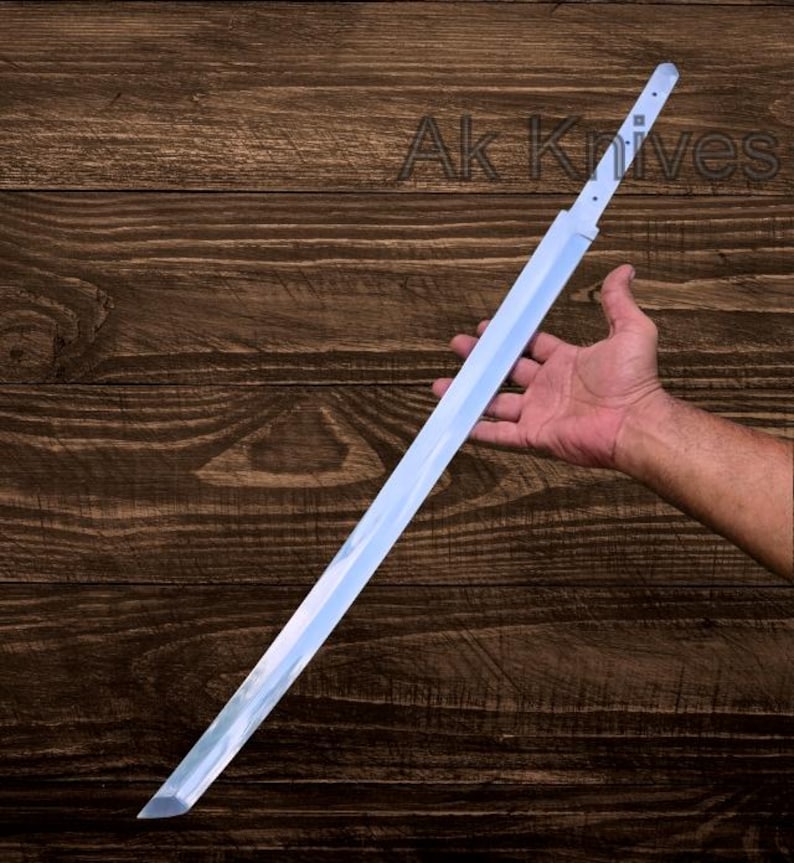 May include: A long, silver-colored sword with a sharp blade. The sword is held in a hand against a dark wood background. The text "Ak Knives" is visible in the upper right corner.