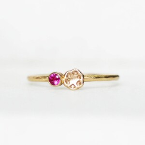 Könnte beinhalten: Ein goldener Ring mit einem rosafarbenen Edelstein und einem strukturierten Golddesign.