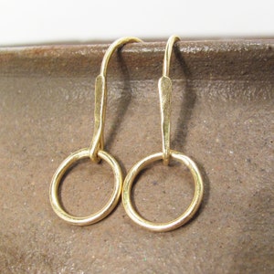 May include: A pair of gold hoop earrings with a simple, minimalist design. The hoops are small and delicate, and the earrings are perfect for everyday wear.