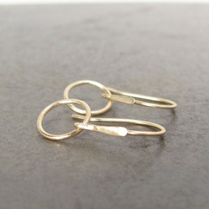 May include: A pair of gold hoop earrings with a simple, minimalist design. The hoops are small and delicate, and the earrings are perfect for everyday wear.