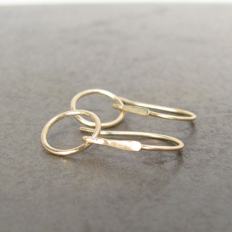 May include: A pair of gold hoop earrings with a simple, minimalist design. The hoops are small and delicate, and the earrings are perfect for everyday wear.