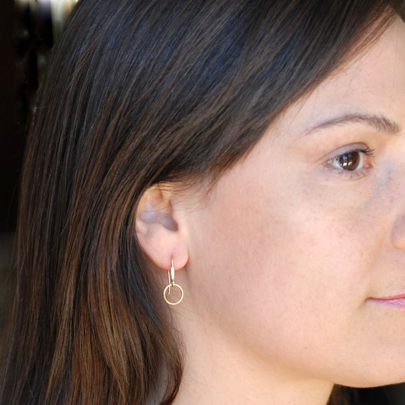 May include: A pair of small, gold hoop earrings. The earrings are simple and delicate, with a smooth, polished finish.