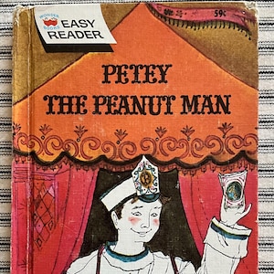 May include: Vintage children's book titled "Petey the Peanut Man." The cover features an illustration of a smiling man in a white uniform and hat, holding peanut packets. The book has an orange background with the text "Easy Reader."