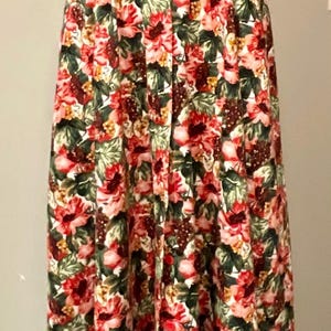 May include: A floral print skirt with a red top. The skirt features a pattern of red, pink, and white flowers with green leaves. The top is a solid, bright red color.