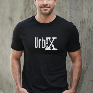 Puede incluir: Camiseta negra de cuello redondo con el texto blanco "Urbex" en el pecho. La "X" de la palabra tiene un diseño texturizado único. La camiseta está hecha de un material suave.