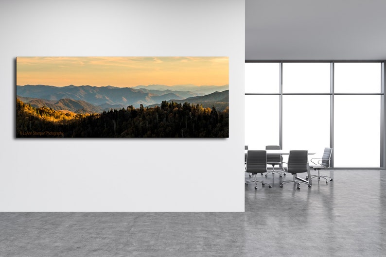 Puede incluir: Una fotograf&iacute;a panor&aacute;mica de una cordillera con un cielo azul y una puesta de sol dorada. Las monta&ntilde;as est&aacute;n cubiertas de &aacute;rboles y el cielo est&aacute; lleno de nubes. La imagen se toma desde un punto de vista elevado, mirando hacia el paisaje.