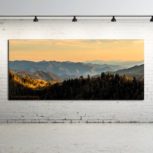 Puede incluir: Una fotograf&iacute;a panor&aacute;mica de una cordillera con una puesta de sol dorada en el fondo. Las monta&ntilde;as est&aacute;n cubiertas de &aacute;rboles, algunos de los cuales est&aacute;n cambiando de color para el oto&ntilde;o. La imagen est&aacute; tomada desde un punto de vista elevado, mirando hacia las monta&ntilde;as.