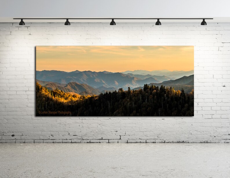 Puede incluir: Una fotograf&iacute;a panor&aacute;mica de una cordillera con una puesta de sol dorada en el fondo. Las monta&ntilde;as est&aacute;n cubiertas de &aacute;rboles, algunos de los cuales est&aacute;n cambiando de color para el oto&ntilde;o. La imagen est&aacute; tomada desde un punto de vista elevado, mirando hacia las monta&ntilde;as.
