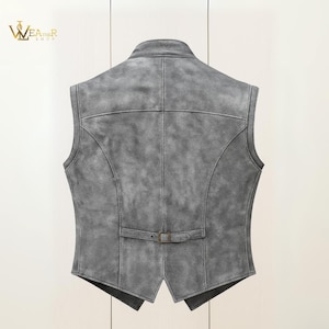 Op de afbeelding: Een grijze leren gilet met een klassiek ontwerp. De gilet heeft een reverskraag, een gespsluiting in de taille en gedetailleerde stiksels. De achterkant toont de getailleerde pasvorm en het getextureerde leer.