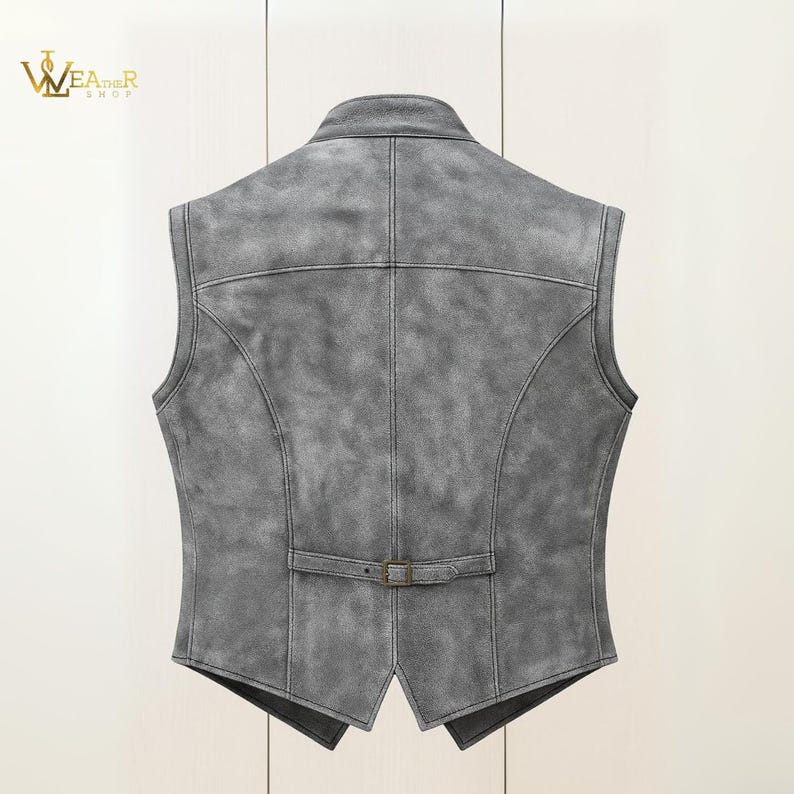 Op de afbeelding: Een grijze leren gilet met een klassiek ontwerp. De gilet heeft een reverskraag, een gespsluiting in de taille en gedetailleerde stiksels. De achterkant toont de getailleerde pasvorm en het getextureerde leer.