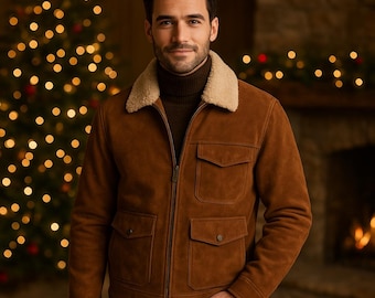 Könnte beinhalten: Braune Wildlederjacke mit cremefarbenem Shearling-Kragen. Die Jacke hat vier Vordertaschen und einen Reißverschluss. Die Person trägt einen braunen Rollkragenpullover. Der Hintergrund umfasst einen Weihnachtsbaum mit Lichtern.