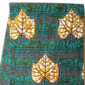May include: A vibrant fabric featuring a repeating pattern of large, stylized yellow and white leaves with brown outlines. The background is a teal and brown brick-like design, creating a bold and eye-catching textile.