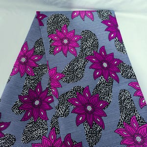 Puede incluir: Una tela con un estampado floral repetitivo. Grandes flores de color rosa brillante se distribuyen sobre un fondo azul claro con finas rayas blancas. Formas abstractas en blanco y negro llenan los espacios entre las flores.