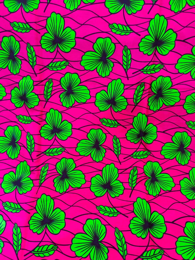 May include: A vibrant fabric featuring a repeating pattern of green shamrock-like leaves and smaller leaves against a bright pink background. The leaves have dark blue-green centers and are outlined in bright green.