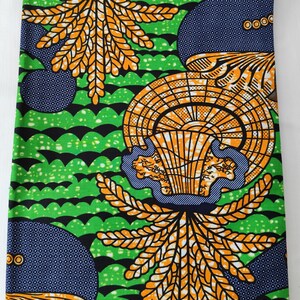 May include: Vibrant fabric with a repeating pattern of orange and yellow leaf-like shapes, blue circles with white dots, and green wavy lines. The design is bold and eye-catching, perfect for various craft projects.