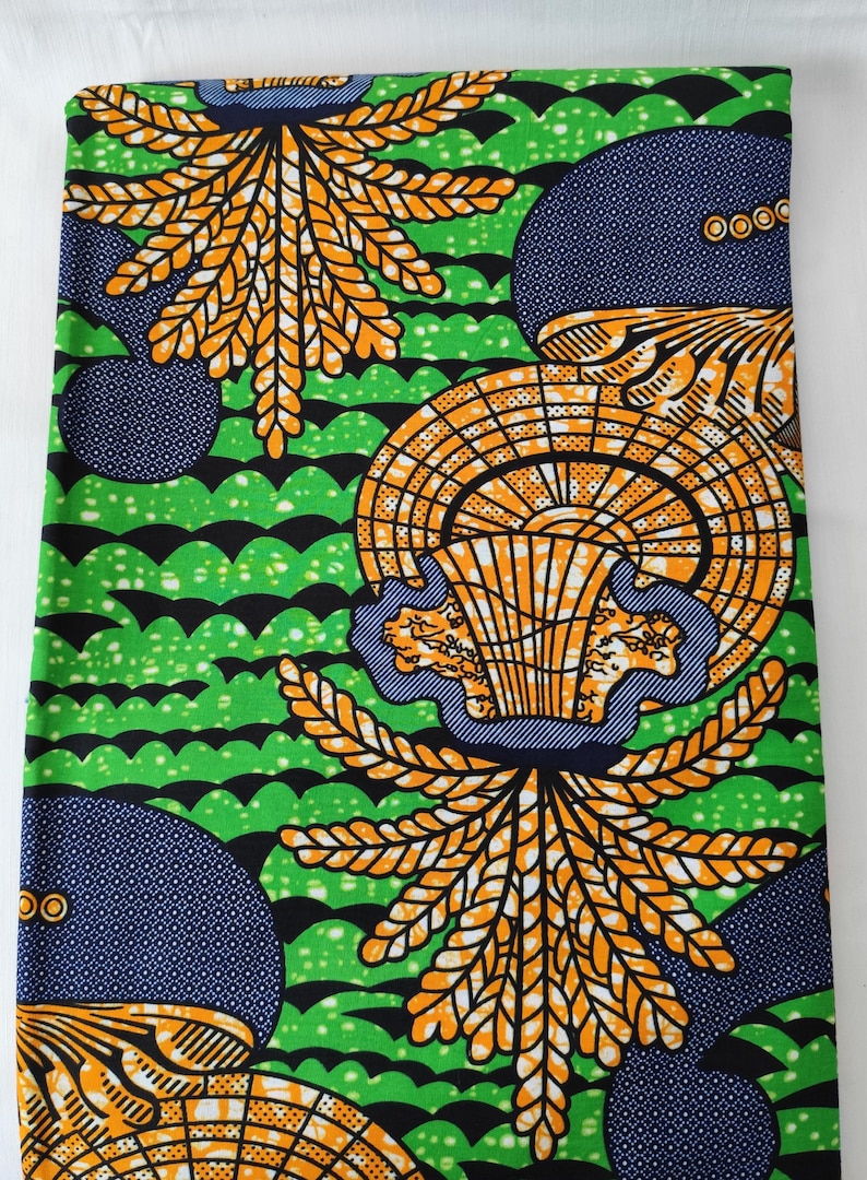 May include: Vibrant fabric with a repeating pattern of orange and yellow leaf-like shapes, blue circles with white dots, and green wavy lines. The design is bold and eye-catching, perfect for various craft projects.
