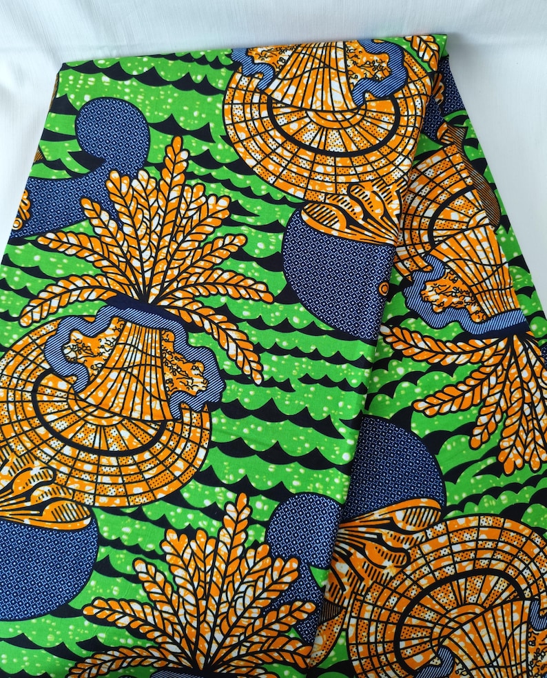 May include: Vibrant green fabric with a repeating pattern of orange and yellow fan-like shapes, blue circular designs, and black wave-like lines. The fabric has a bold, colorful design.