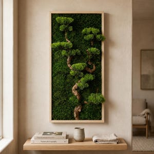 May include: A rectangular wall art piece featuring a vertical wooden frame filled with deep green preserved moss and a central, winding brown branch with clusters of bright green pine needles extending outward from the textured mossy surface.