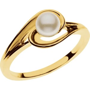 May include: A gold-colored ring featuring a white pearl. The ring's design has a flowing, openwork style, with the pearl set in a swirling, decorative setting. The band is smooth and polished.