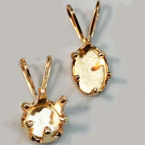 May include: Two gold-tone pendant settings for jewelry making. One setting is round and the other is oval.