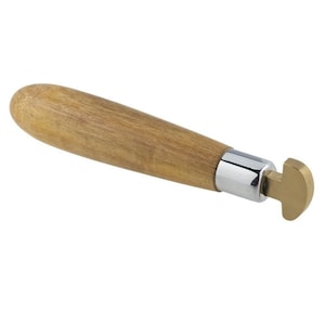 Puede incluir: Una herramienta con mango de madera y cabeza de metal y latón. La herramienta se utiliza para dar forma al metal.