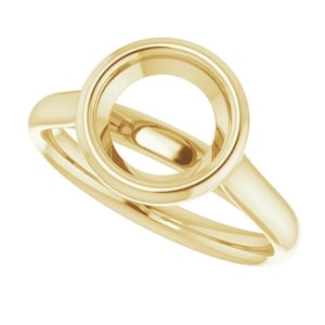 May include: A gold-colored ring with a circular setting and a split shank design. The ring's setting is a prominent circle, and the band curves around the finger. The ring is made of a shiny, polished metal.