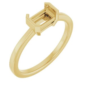 May include: A gold ring with an emerald-shaped setting. The setting is open and ready to hold a gemstone.