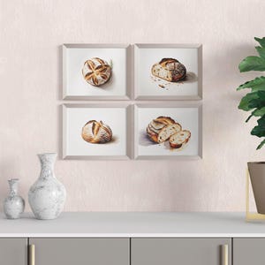 Puede incluir: Cuatro acuarelas enmarcadas de pan de masa madre, expuestas en una pared blanca sobre una encimera gris con dos jarrones de cerámica blanca y una planta en maceta con hojas verdes en una maceta marrón sobre un soporte dorado.