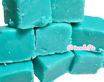 May include: A stack of turquoise fudge squares. The fudge has a smooth, slightly glossy surface and is cut into irregular, bite-sized pieces. The image includes the text "Prince & Pie".
