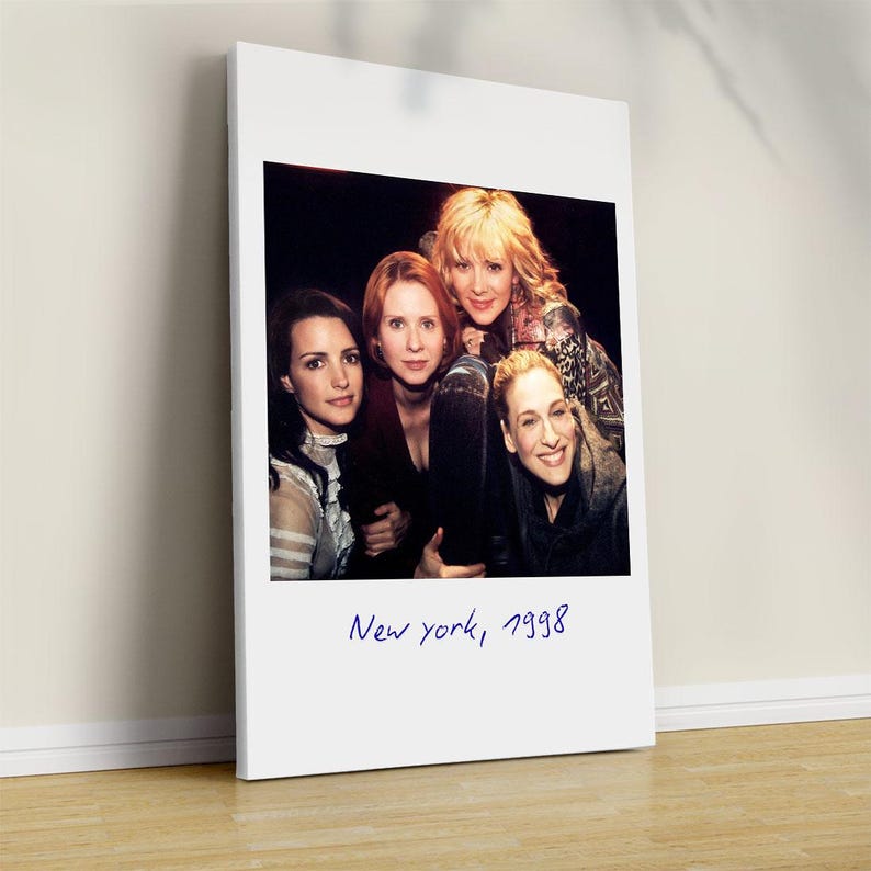 May include: A framed print featuring a group of four women posing for a photo. The image is a vintage-style photograph with the text "New York, 1998" written in blue script at the bottom. The women are smiling and looking at the camera.