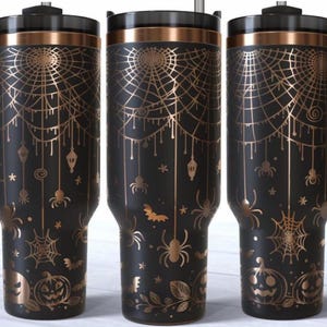 May include: Black insulated travel mug with a handle, decorated with a gold spiderweb, spiders, bats, and pumpkins. The mug has a black lid and a gold rim, ideal for Halloween.