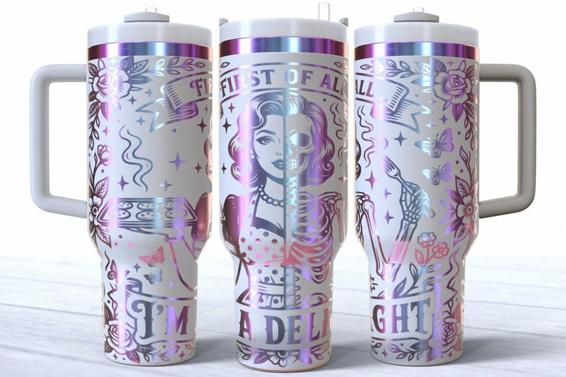 May include: White tumbler with a handle, featuring a design with a woman's face, half skull, and the text "FIRST OF ALL I'M A DELIGHT". The design includes flowers, butterflies, and a skeleton hand holding a fork, with iridescent accents.