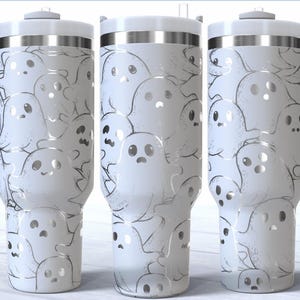 May include: White tumbler with a wraparound design of cartoon ghosts in various expressions. The tumbler has a white handle, lid, and a silver band. The design is in a sketched style, perfect for Halloween or spooky season.