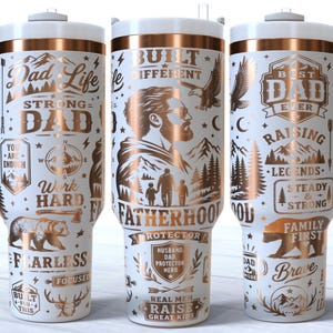 May include: White insulated tumbler with a handle, featuring gold and black graphics. The design includes text like "Dad Life," "Strong Dad," and "Best Dad Ever," along with illustrations of bears, mountains, and eagles. The tumbler is approximately 9 inches tall.