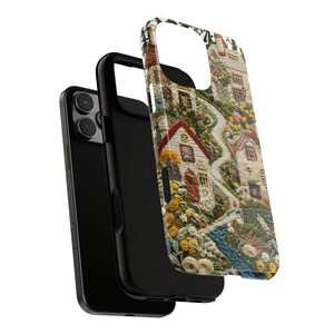 May include: A black smartphone with a protective case featuring a detailed tapestry design of a village scene. The case showcases houses, a winding path, and colorful flowers. The case is detached from the phone, revealing the phone's black back.