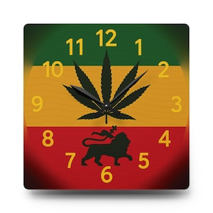 Op de afbeelding: Vierkante wandklok met een groene, gele en rode achtergrond. De wijzerplaat heeft een zwart cannabisblad, een leeuwensilhouet en gele cijfers. De wijzers zijn zwart.