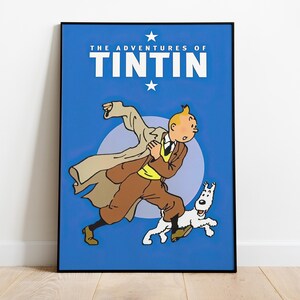 May include: A framed poster featuring a cartoon image of Tintin running with his dog Snowy. The poster has a blue background with the words "THE ADVENTURES OF TINTIN" in white. The cartoon character is wearing a brown suit and tan overcoat.