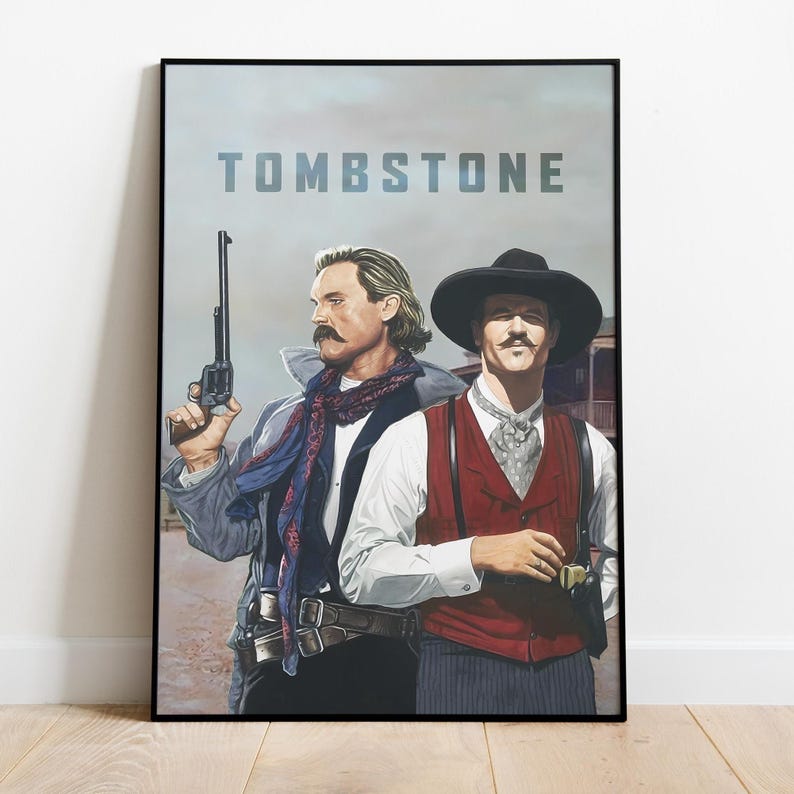 May include: A poster for the movie "Tombstone" featuring two men in cowboy attire. The man on the left is holding a gun and wearing a blue scarf. The man on the right is wearing a red vest and a black hat.