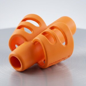 May include: Bright orange ergonomic pen grip with a cylindrical shape and multiple finger holes. The product is labeled "ERGOGRIP PRO 3D" and is designed to improve writing comfort and control. The grip is made of a smooth, matte material.