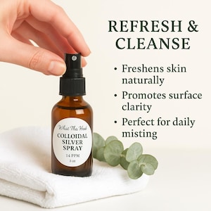 May include: A brown glass spray bottle labeled "What Tha Hert COLLOIDAL SILVER SPRAY 14 PPM 2 oz" is held over a white towel. The text "REFRESH & CLEANSE" and product benefits are displayed in green text.