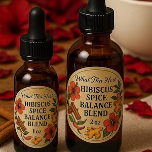 Op de afbeelding: Twee bruine glazen flessen met zwarte druppelaars. De flessen zijn gelabeld met "What Tha Herb Hibiscus Spice Balance Blend" met bloemen- en kruidenillustraties. Eén fles is 1 oz, de andere is 2 oz.