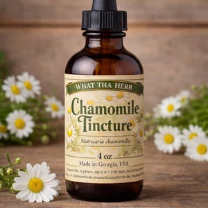 May include: A brown glass bottle of Chamomile Tincture with a black dropper. The label reads "WHAT THA HERB Chamomile Tincture" with the scientific name Matricaria chamomilla. The bottle contains 118 ml of liquid and is made in Georgia, USA. White daisies are in the background.