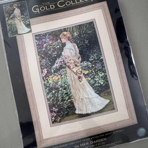 Puede incluir: Un kit de punto de cruz contado de Dimensions Gold Collection titulado "In Her Garden". La imagen muestra a una mujer con un vestido blanco en un jardín. El kit mide 28 x 41 cm (11 x 16 pulgadas).