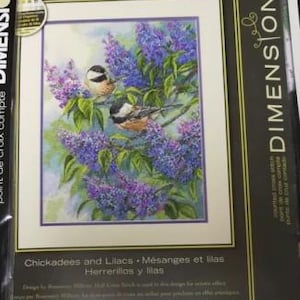 Puede incluir: Un kit de punto de cruz contado Dimensions Gold Collection titulado Chickadees and Lilacs. El empaque presenta una ilustración de dos carboneros posados en ramas de lilas moradas. El kit mide 30 cm por 40 cm según lo impreso.
