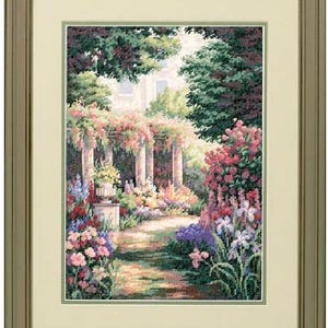 May include: A framed cross-stitch embroidery depicting a lush garden scene with a stone pergola, a central pathway, and vibrant clusters of pink, blue, and purple flowers. The artwork is encased in a simple, light-colored wooden frame with a mat.