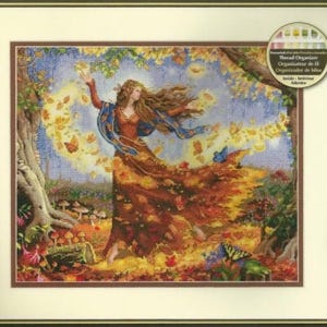 May include: A cross-stitch kit featuring a woman with long brown hair in a flowing dress made of autumn leaves, surrounded by swirling yellow leaves and butterflies in a forest setting with mushrooms, including a thread organiser sticker.